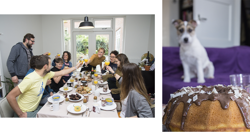 Two photos: the first is a photo of a group of people sitting at a table full of food. They are leaning over the table to toast each other. The second photo is a photo of a cake with a dog in the background.